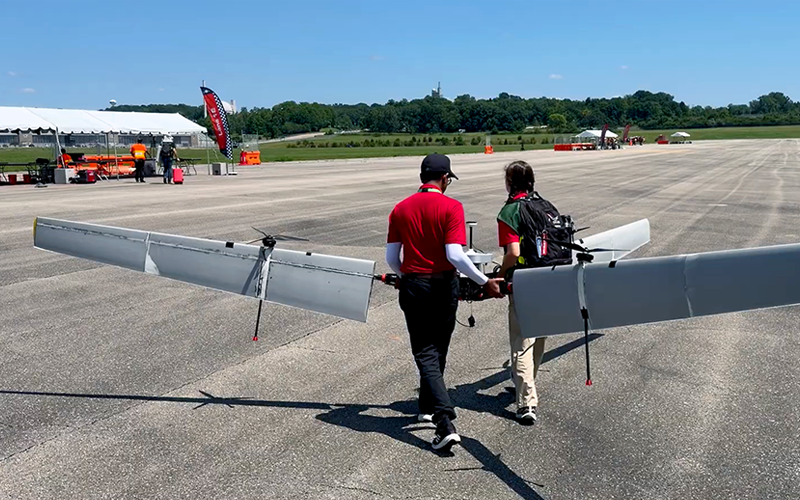 Students carrying a large UAS across an airfield